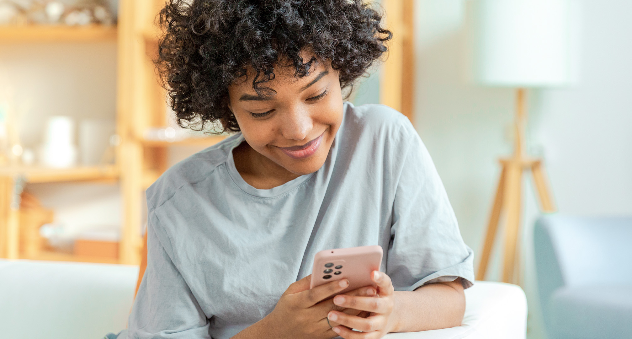 lähikuva henkilöstä, joka hymyilee ja katsoo puhelintaan